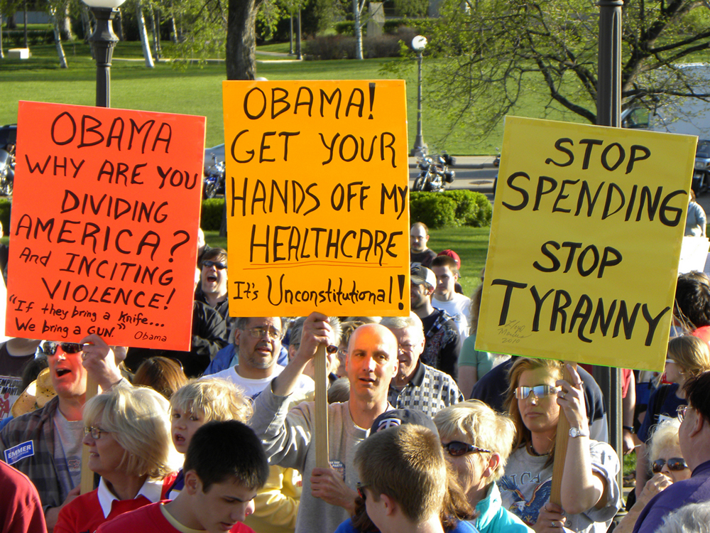 A group of protesters holding signs protesting federal health care changes are shown here.