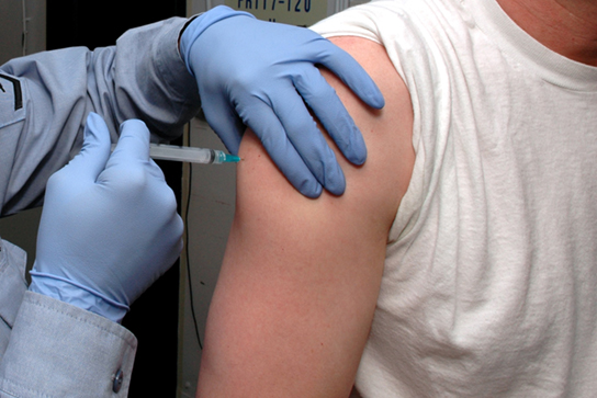 Photo shows a person receiving an injection in the arm.