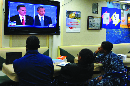 An image of three people watching a television. On the television screen are Mitt Romney and Barack Obama.