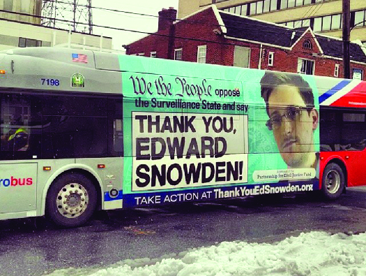 An ad on the side of a bus featuring a photo of Edward Snowden. The text says “We the people oppose the Surveillance State and say ‘Thank you, Edward Snowden!’”