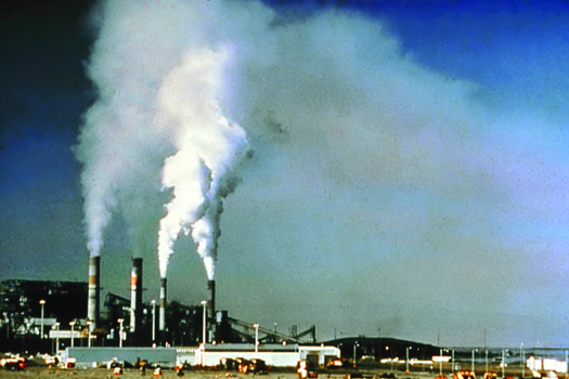 An image of a power plant with large columns of smoke billowing out of its four towers.