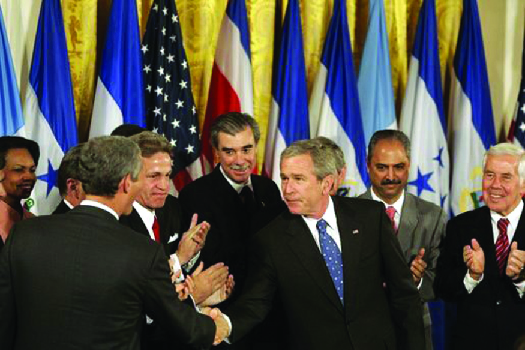 An image of George W. Bush shaking hands with legislators and administration officials.