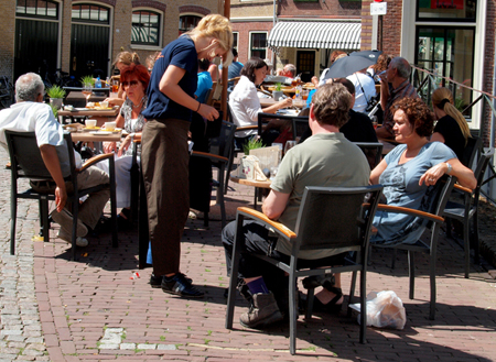 Waitress serves customers in an outdoor café.